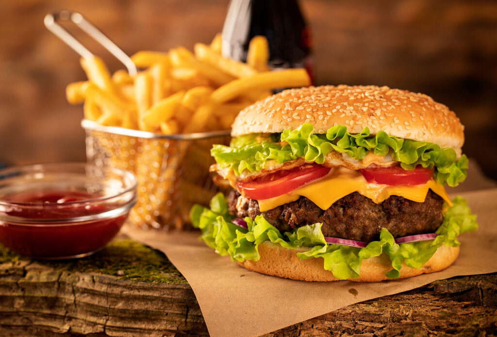 Saftiger Burger mit Salat, Tomaten, Käse und Pommes