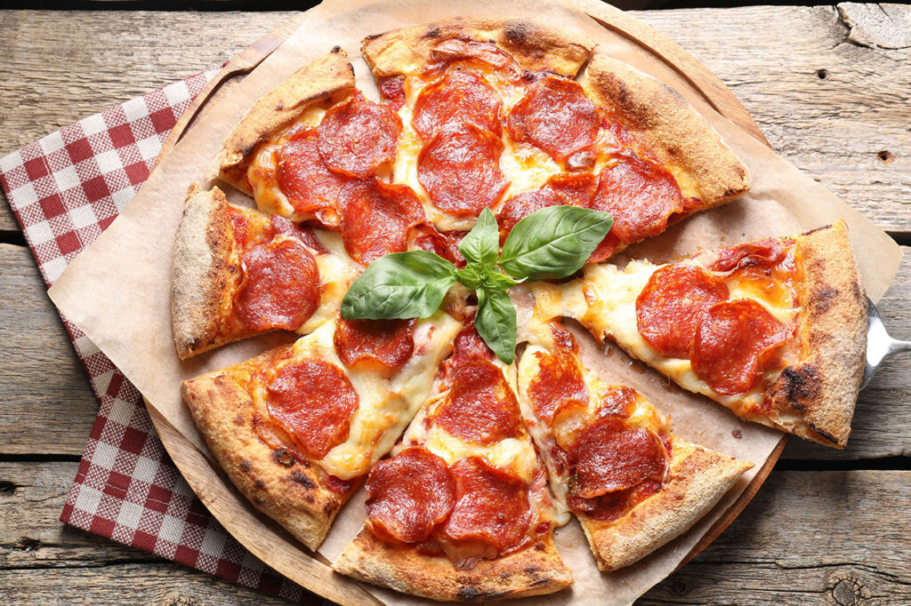 Knusprige Salami Pizza mit geschmolzenem Käse und Basilikum
